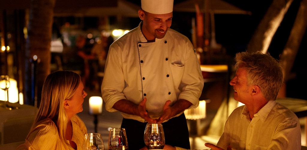 chef talking with couple at dinner